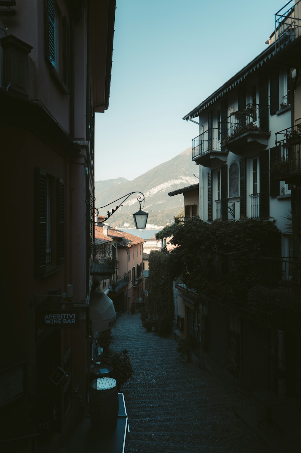 a narrow street with buildings and a mountain in the background