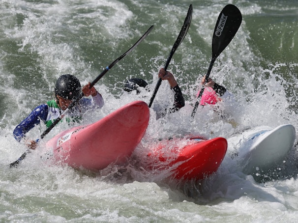 Safety kayakers attentively watching over the swimmers, paddling beside them in bright boats.