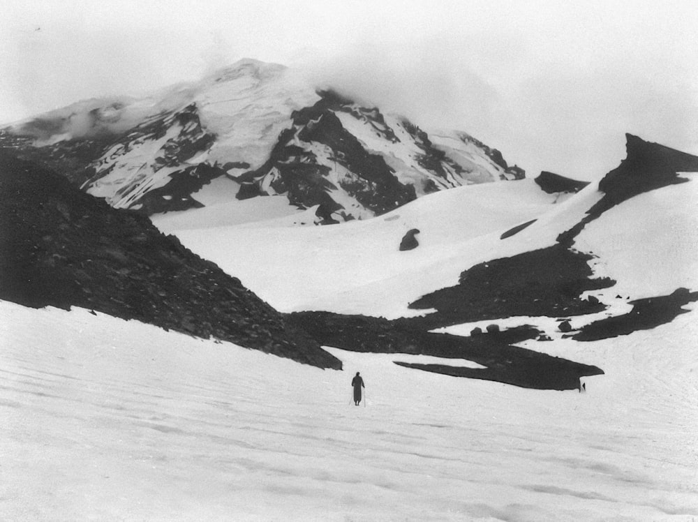 a black and white photo of a person walking in the snow