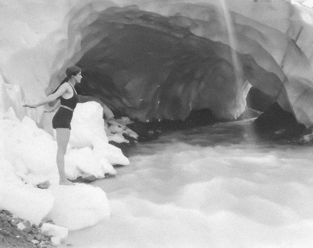 a woman in a bathing suit standing in front of a cave