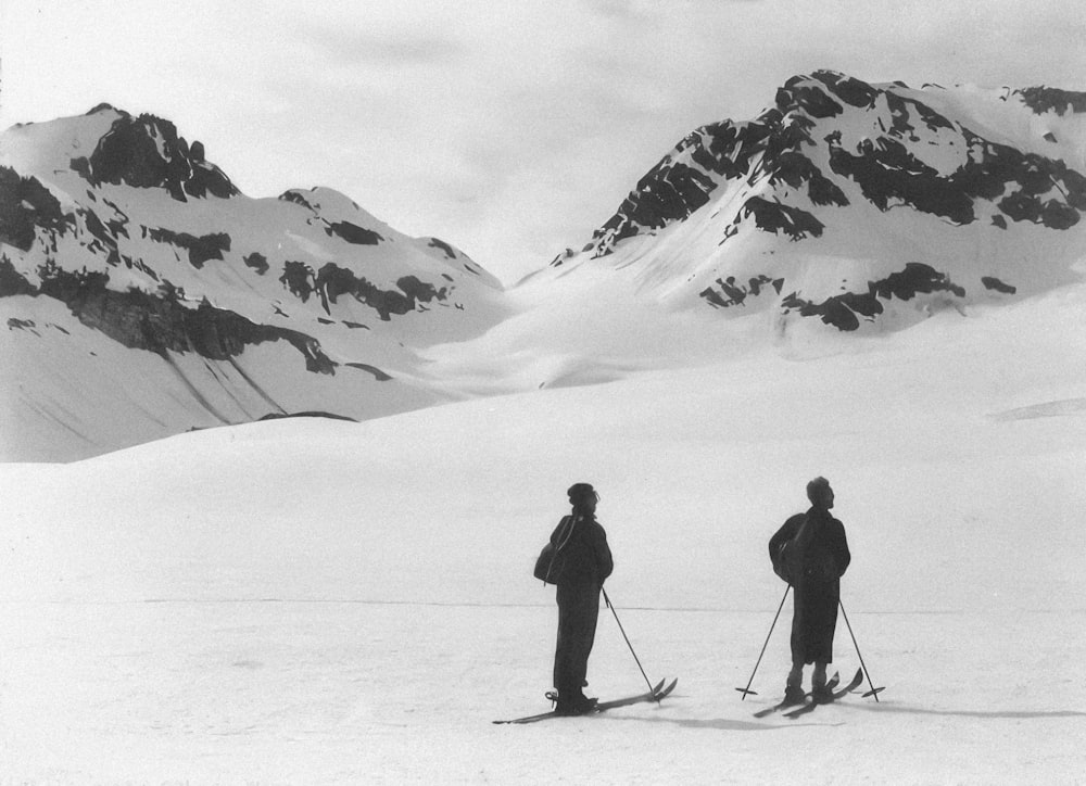 a couple of people riding skis on top of a snow covered slope