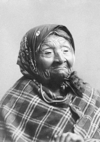 Close-up of an elderly woman smiling gently while participating in a Quran recitation event at Nurziarah.