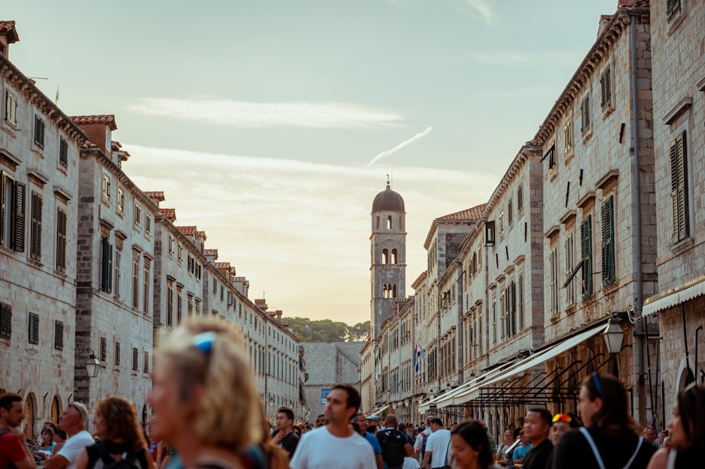 a crowd of people walking down a street next to tall buildings