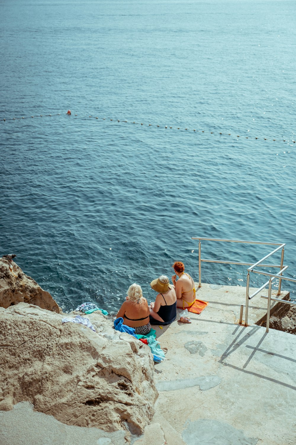 two women sitting on the steps overlooking the water