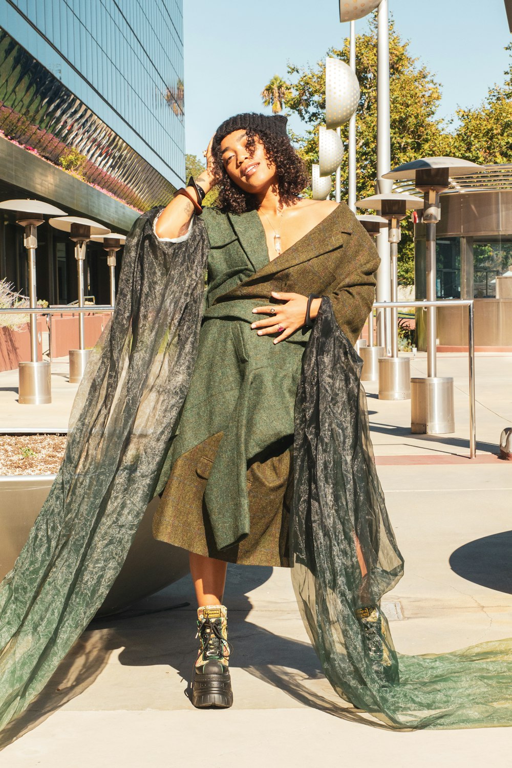 a woman in a green dress standing on a sidewalk