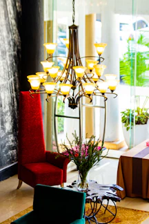 A cozy living room softly illuminated by a warm-toned decorative chandelier hanging above a wooden coffee table.