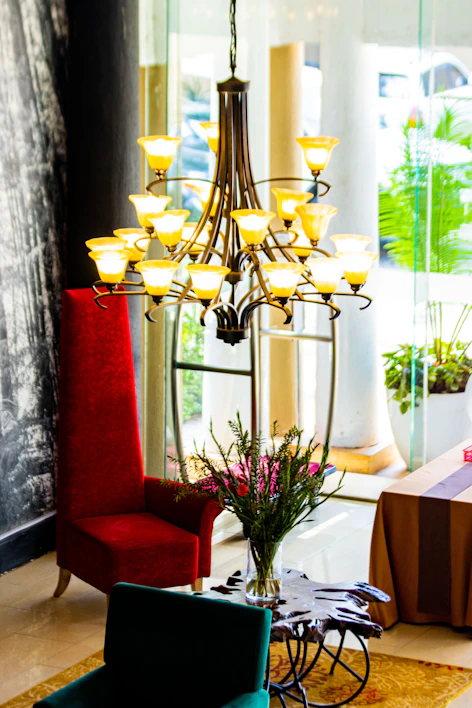 A cozy living room softly illuminated by a warm-toned decorative chandelier hanging above a wooden coffee table.