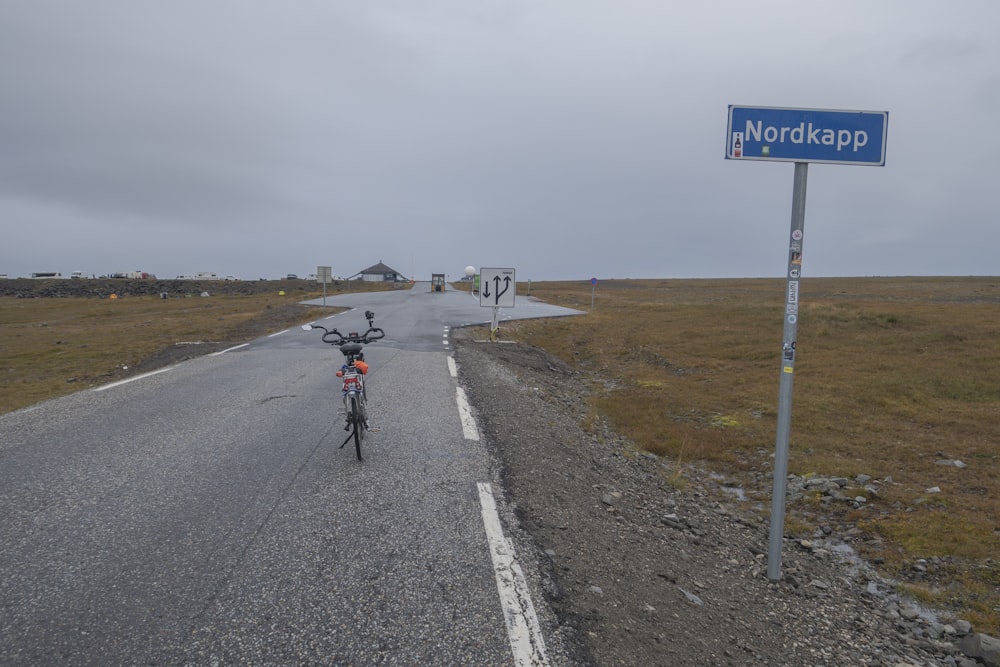 a person riding a bike down a road next to a street sign