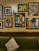 A collection of colorful wall art pieces displayed above a modern sofa in a bright living room.