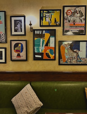 A collection of colorful wall art pieces displayed above a modern sofa in a bright living room.