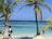 Smiling travelers enjoying a sunset on a tropical beach with clear blue waters.
