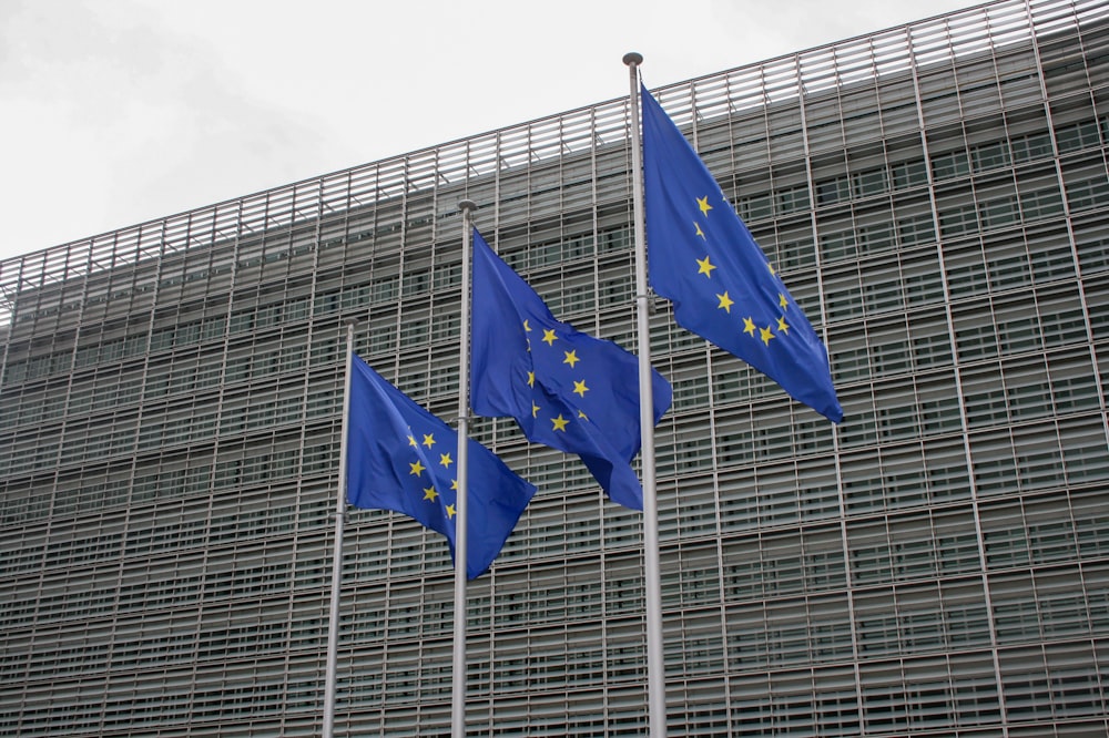 three european flags flying in front of a building