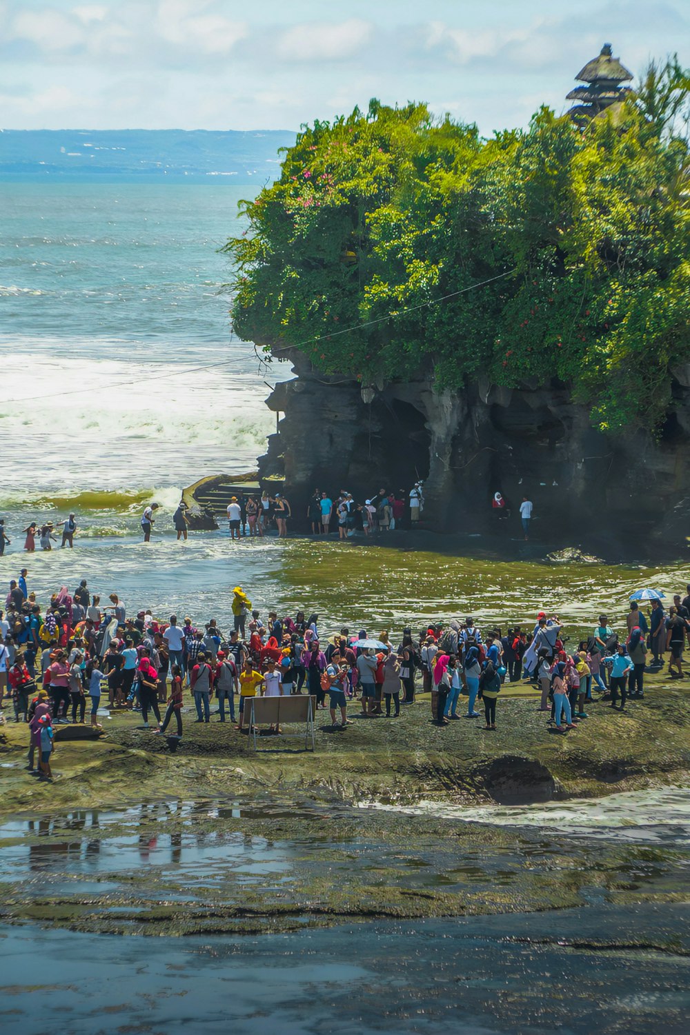 a group of people standing on a beach next to the ocean