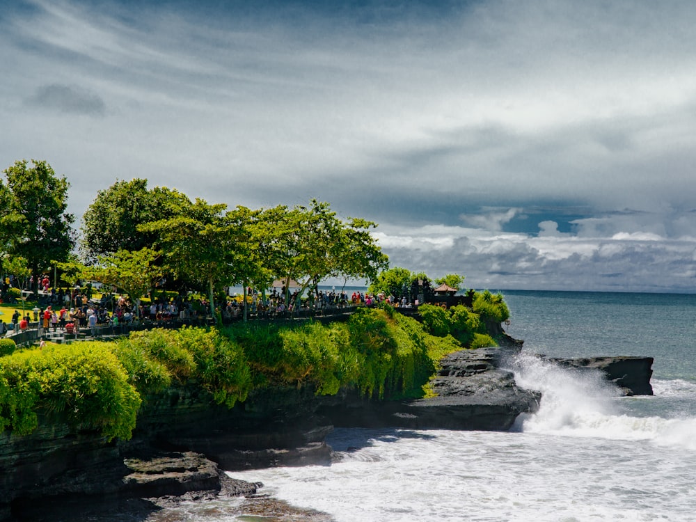 a group of people standing on top of a cliff next to the ocean