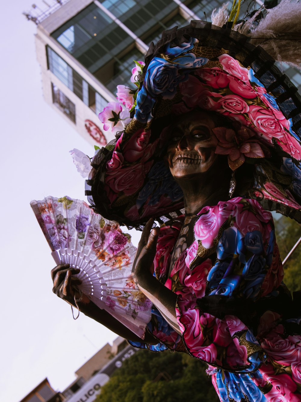 a skeleton wearing a colorful dress and holding a fan