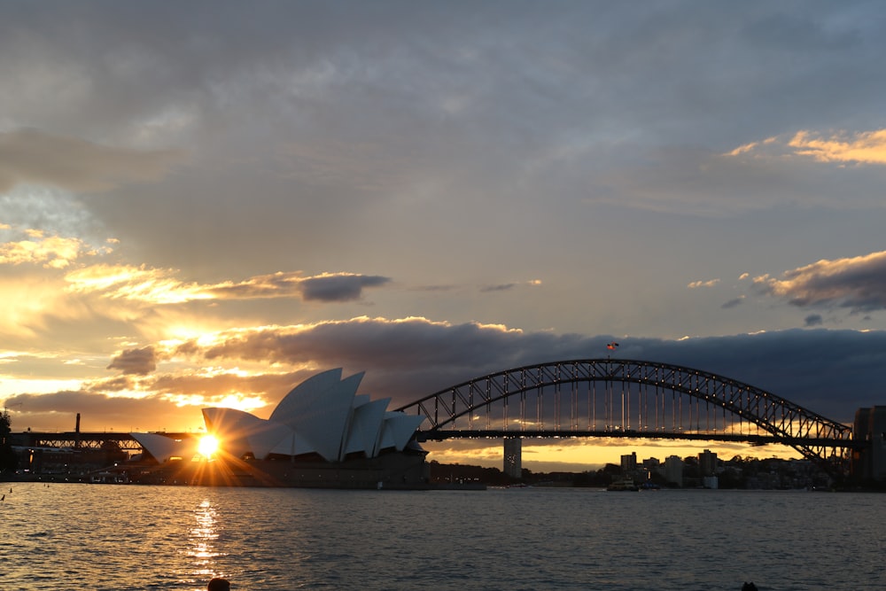 the sun is setting over the sydney opera house