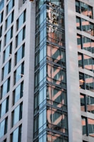 a tall building with a reflection of a clock on it's side