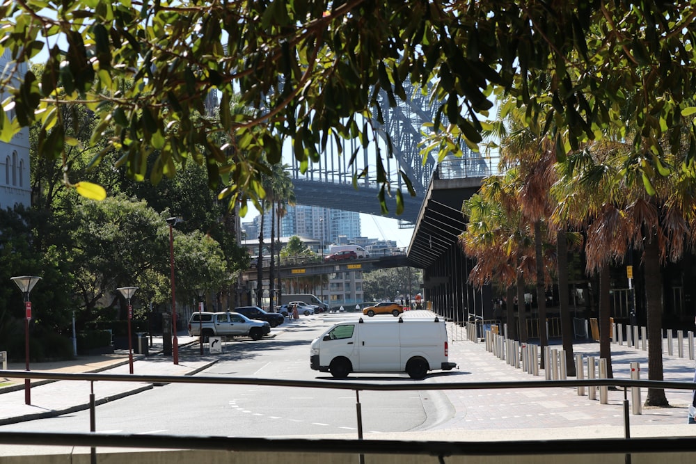 a white van driving down a street next to a bridge