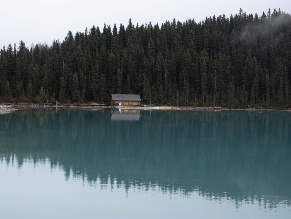 a small cabin sits on the edge of a lake