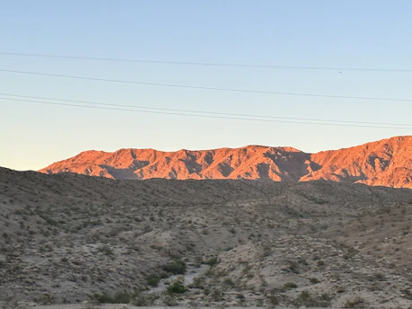 Sunrise over a peaceful off-grid desert homestead in Dteland, AZ, with solar panels and rugged terrain.