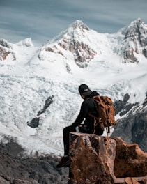 a man with a backpack sitting on a rock
