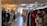 A clothing store interior featuring racks of diverse garments on both sides. The store includes various types of clothing, with organized sections and a mannequin dressed in casual attire. Warm lighting from hanging lamps creates a cozy atmosphere.