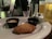 A close-up view of a plate with a single chicken wing placed in front of two small sauce cups. A glass of beer, salt and pepper shakers, and a dark table setting are visible in the background, suggesting a casual dining atmosphere.