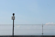Wide shot of a residential property secured with cameras and electronic gates under a clear sky.