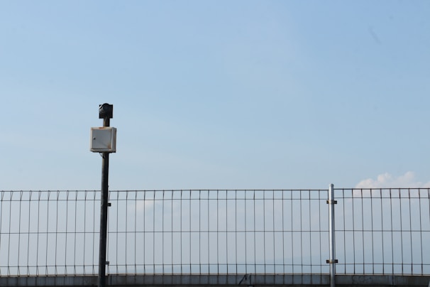 A sturdy security fence installed around an industrial site under a clear blue sky.
