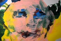 An abstract painting with swirling patterns and vibrant colors, featuring a human-like face with expressive brush strokes. The face is crafted by overlaying shades of pink with dark blue, green, and yellow accents, creating a sense of movement and depth.