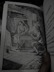 Simple black and white illustration of two people talking over a table.