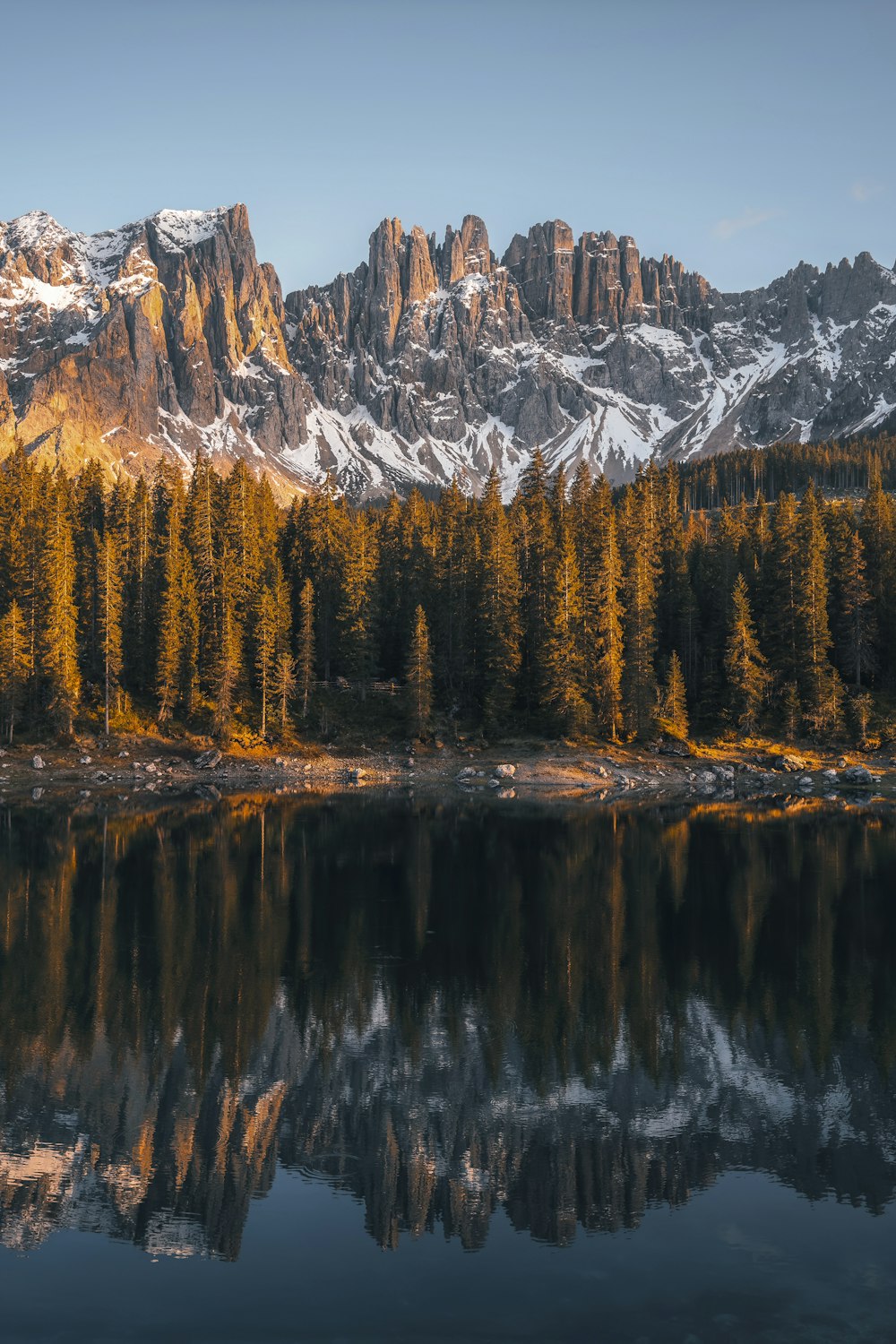 a mountain range is reflected in the still water of a lake