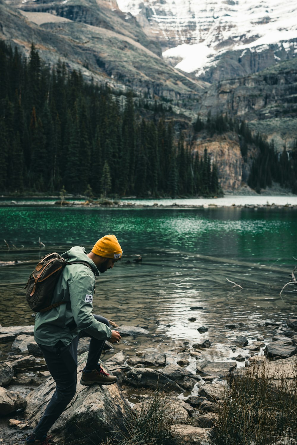 a man with a backpack is standing on a rock near a lake