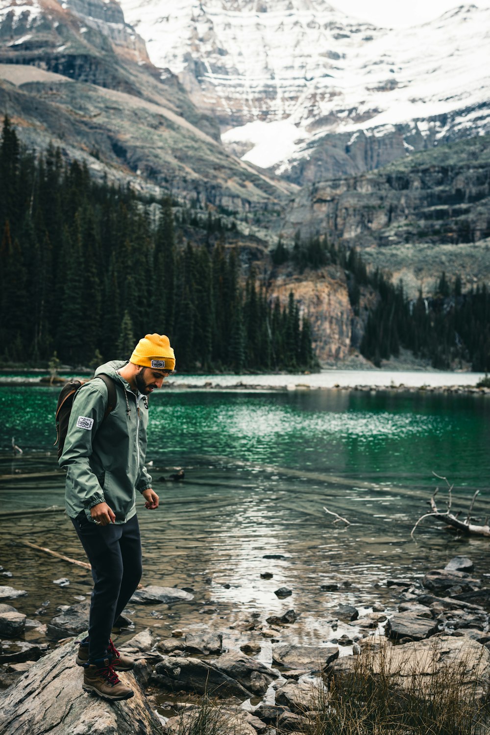 a man standing on a rock next to a lake