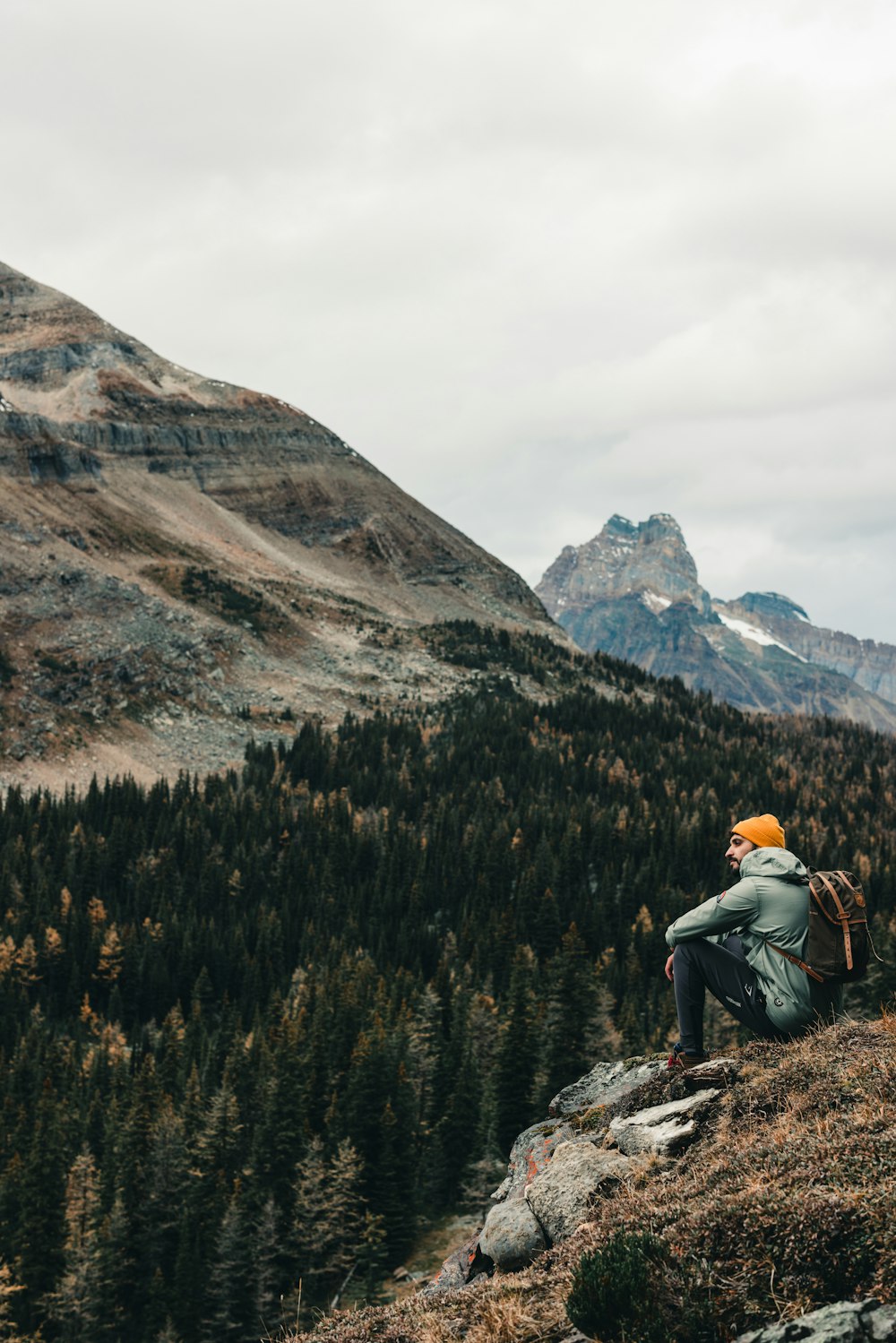 um homem sentado no topo de uma montanha com uma mochila