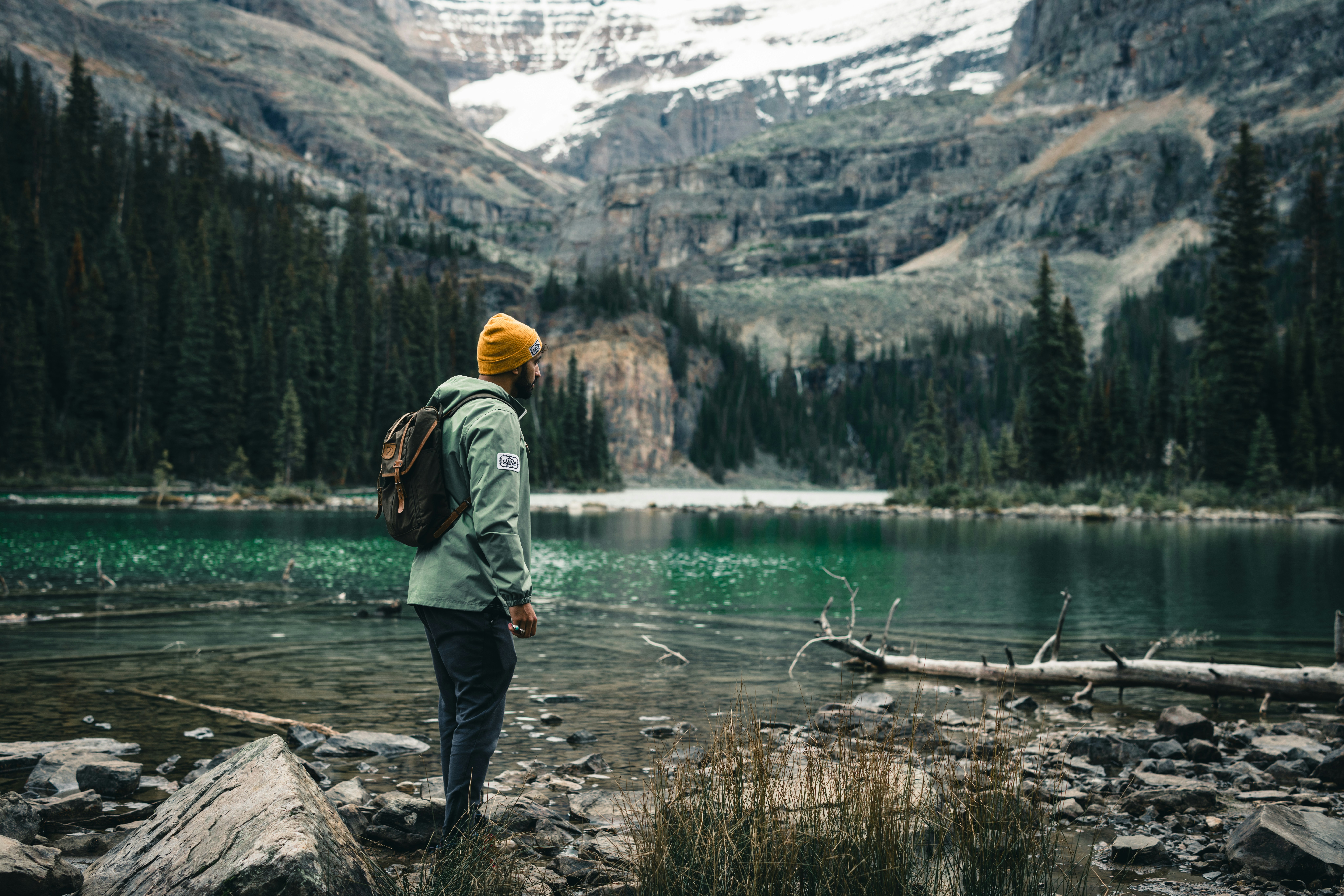 a man standing on a rocky shore looking at a mountain lake, Exploring Yoho