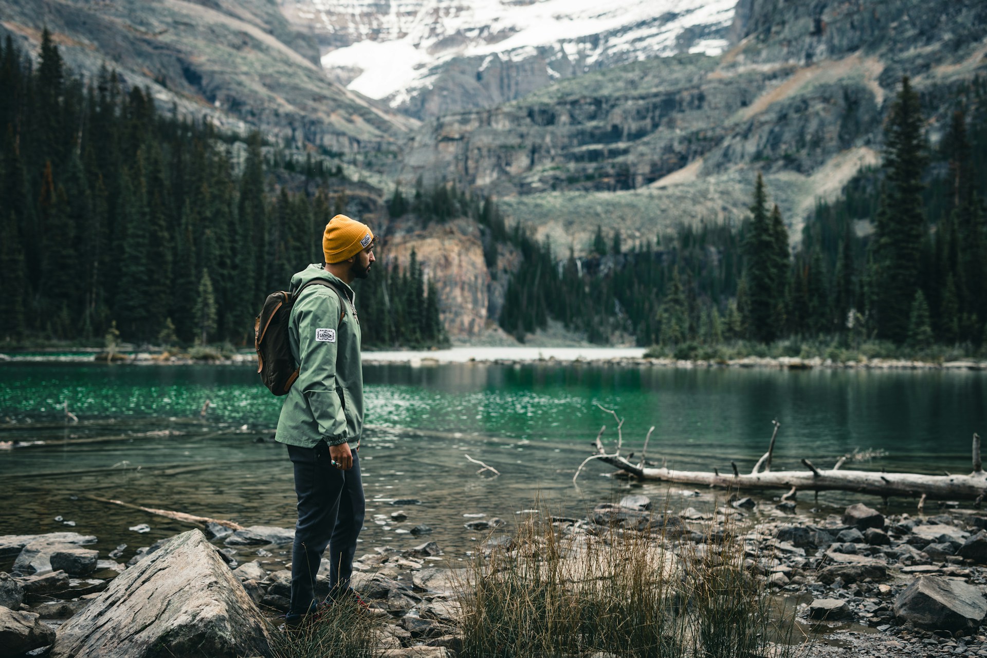 a person standing on a rocky shore near a mountain lake