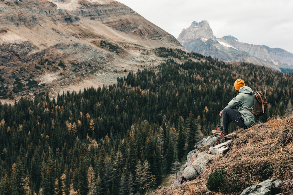 a person sitting on a hill with a backpack