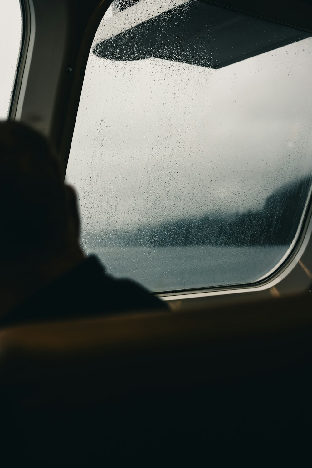 a person looking out a window on a rainy day