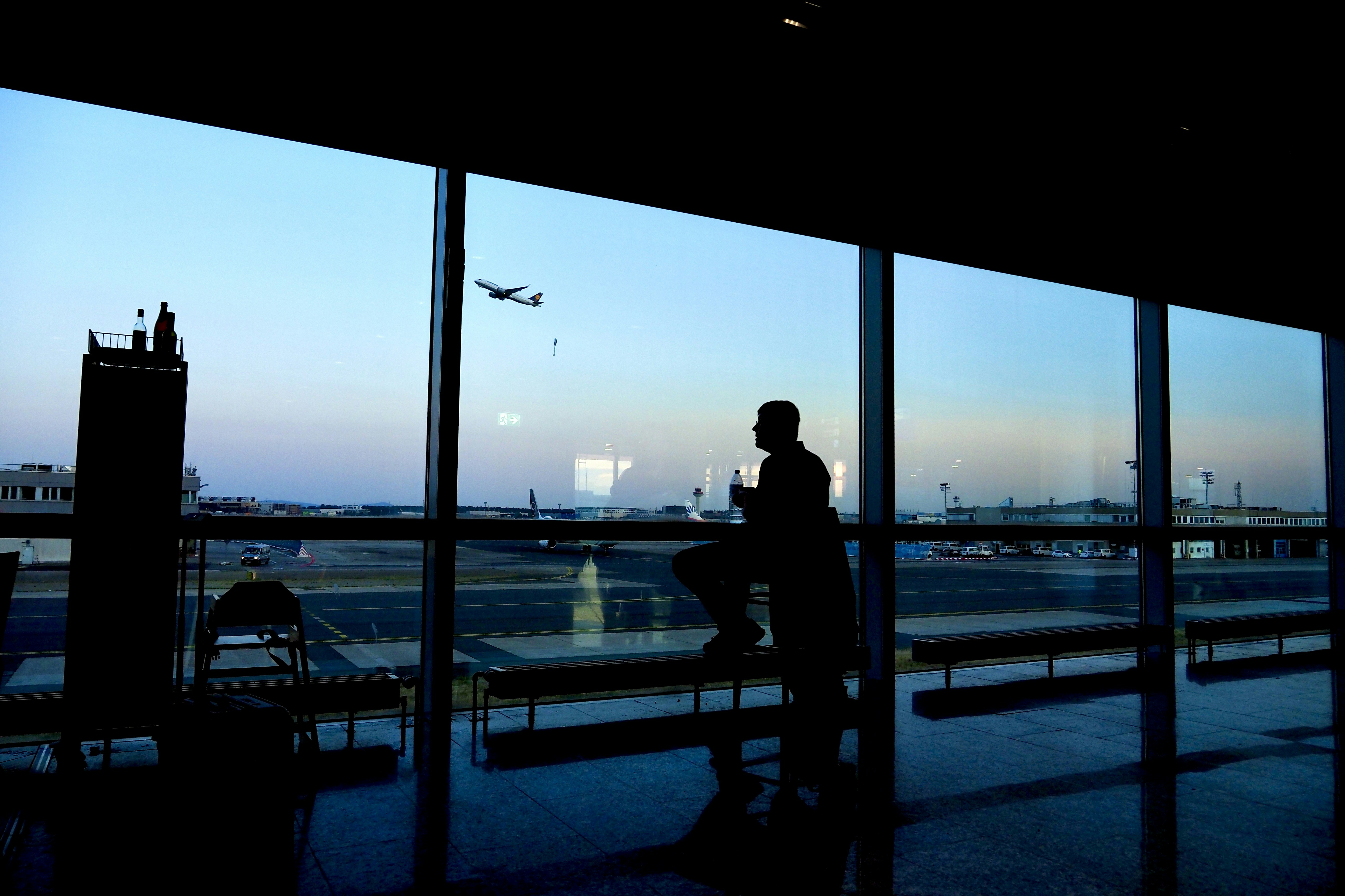 a silhouette of a person sitting in an airport, 