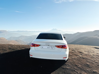 A scenic view of the Atlas Mountains with a luxury vehicle parked nearby.