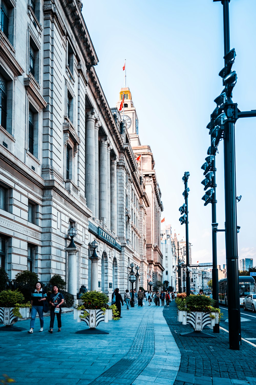 a group of people walking down a street next to tall buildings