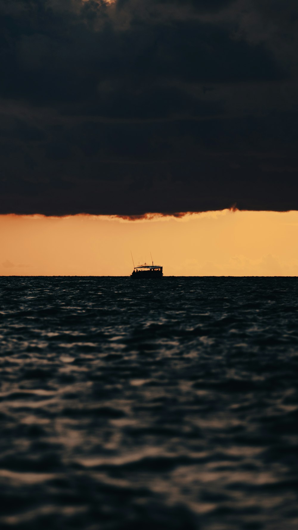 a boat in the middle of the ocean under a cloudy sky