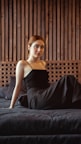 a woman in a black dress sitting on a bed