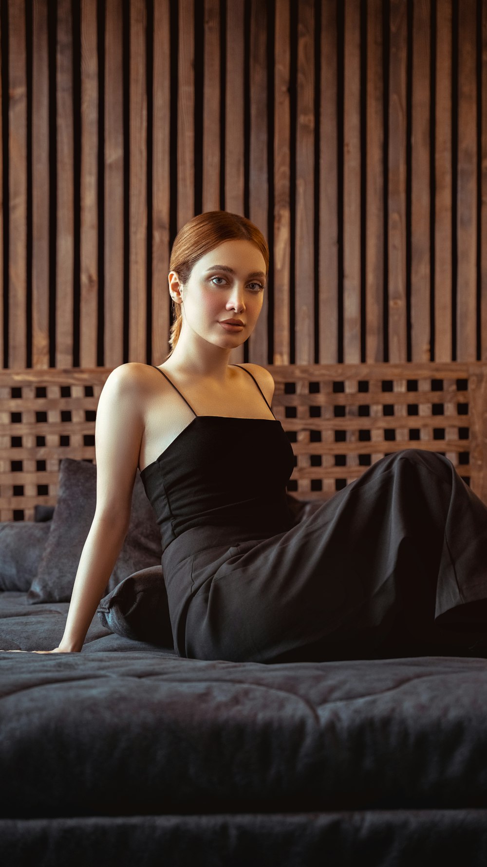 a woman in a black dress sitting on a bed