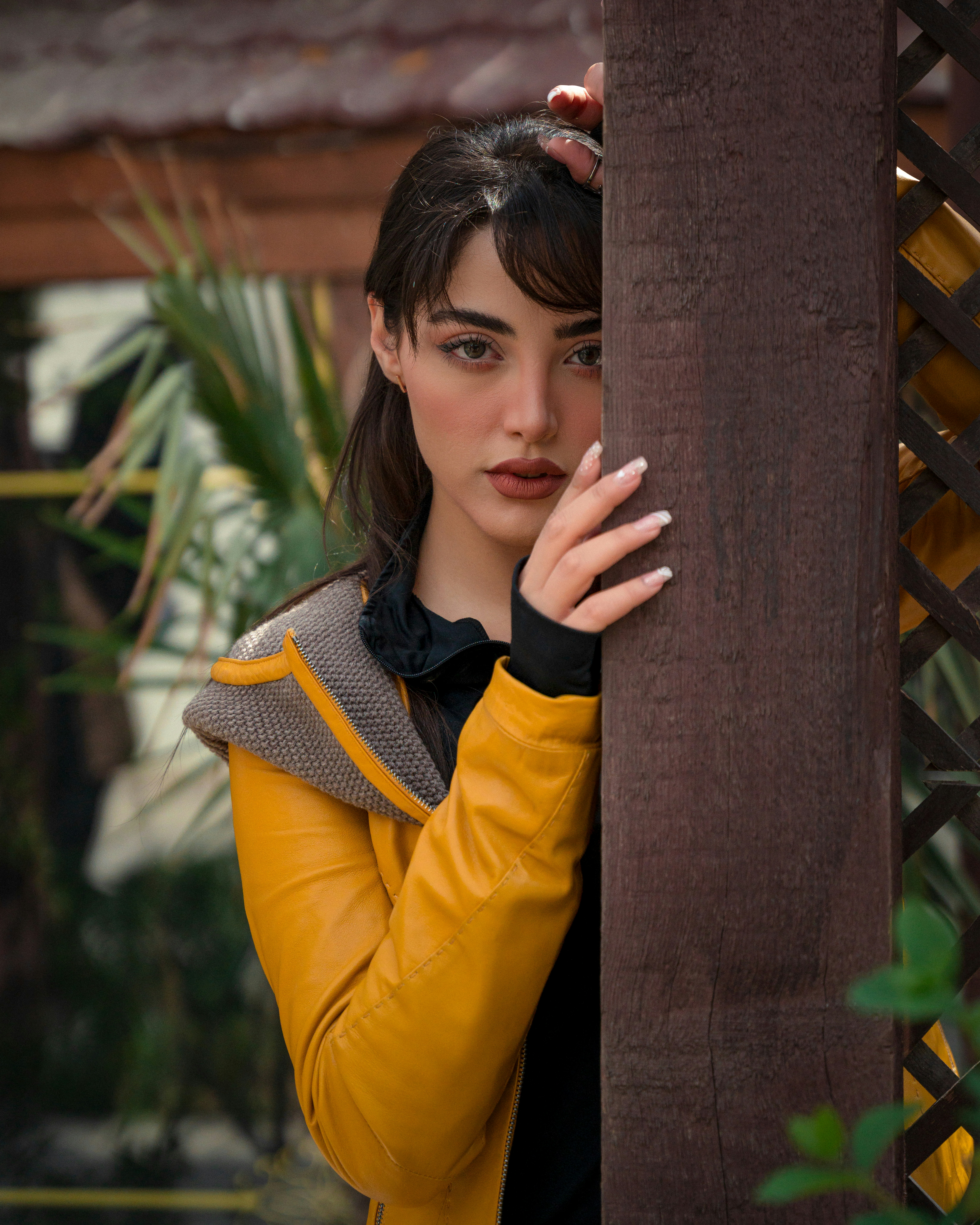 a woman leaning against a wooden structure with her hand on her face