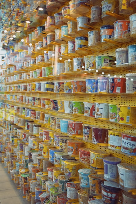 A colorful assortment of ramen noodle packages from various countries stacked neatly on a wooden table.