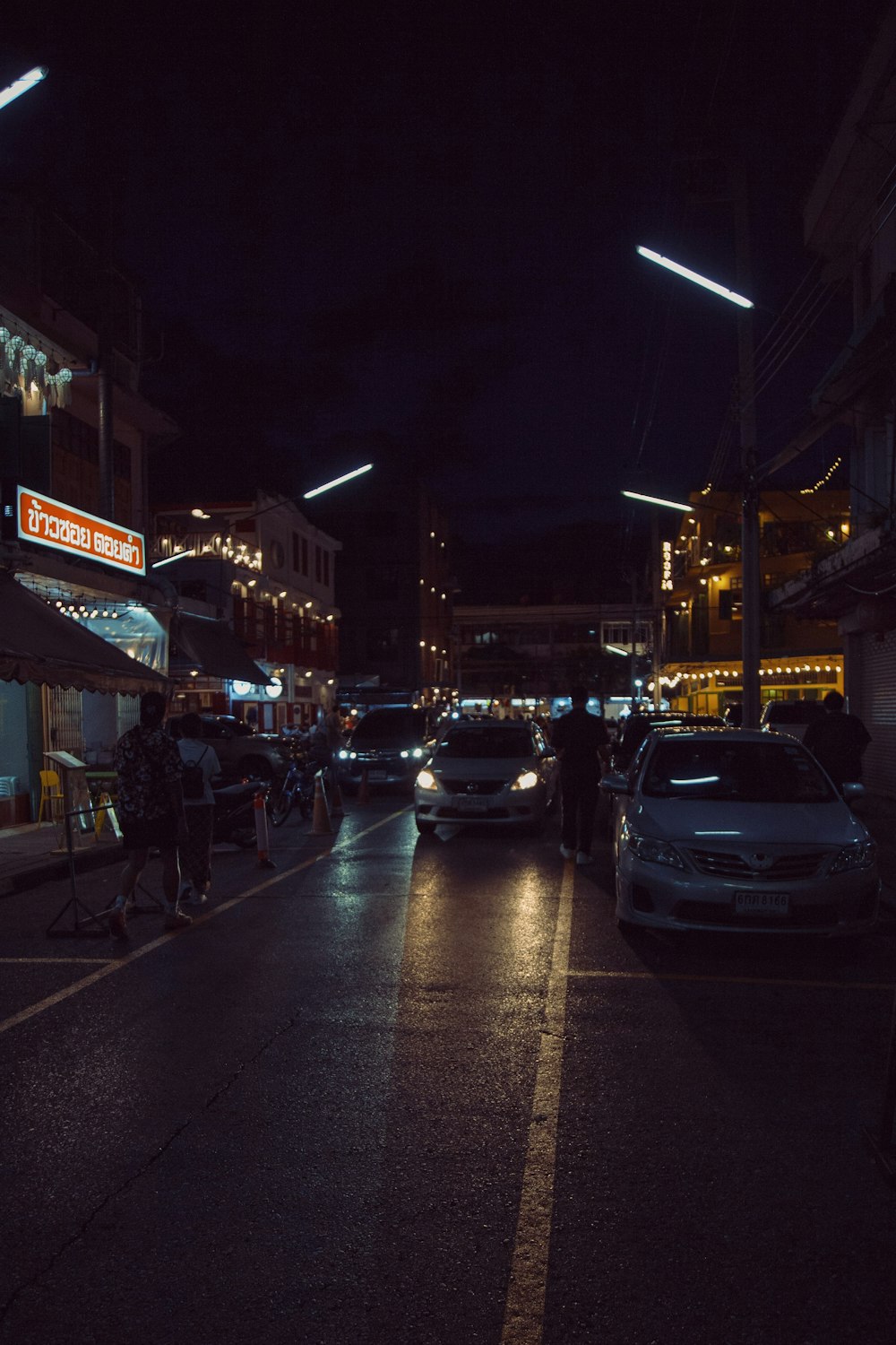 a city street at night with cars parked on the side of the road