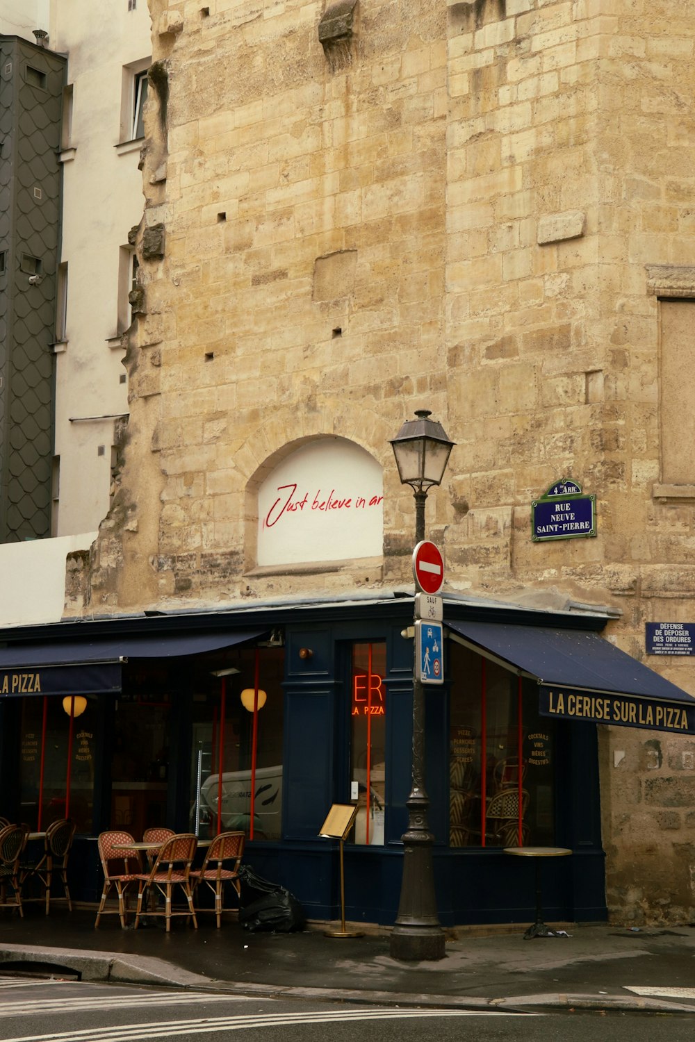 eine Straßenecke mit Tischen und Stühlen vor einem Restaurant