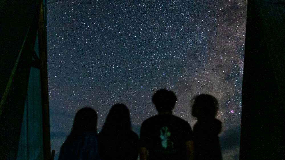 a group of people standing next to each other under a night sky filled with stars